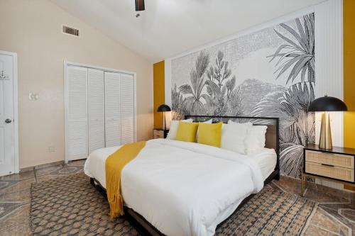 una camera da letto con un grande letto bianco con cuscini gialli di La Casita - Pool, Patio, Pacman! a Euless