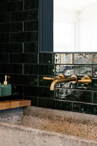 a bathroom sink with a bronze faucet on a brick wall at A Farmhouse escape 15 minutes from Launceston in Carrick