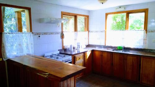 eine Küche mit Holzschränken, einem Herd und Fenstern in der Unterkunft Nuestra Ruca in San Martín de los Andes