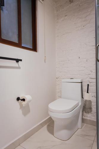 a white bathroom with a toilet and a roll of toilet paper at Agata Hotel Boutique & Spa in Mexico City