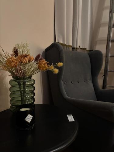 a vase with flowers on a table next to a chair at Your Haven of Peace! in Brussels
