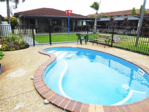 a swimming pool with a brick pathway around it at Tropic Coast Motel in Mackay