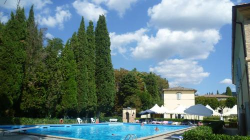 a large swimming pool with trees and a building at Hotel Villa San Donino in Città di Castello