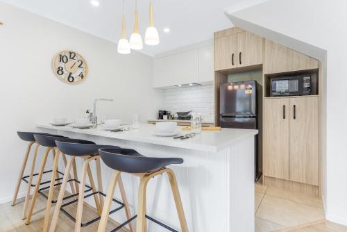 a kitchen with a large white counter with stools at Spacious Stunner! Central, King Bed -By KOSH BNB in Hamilton