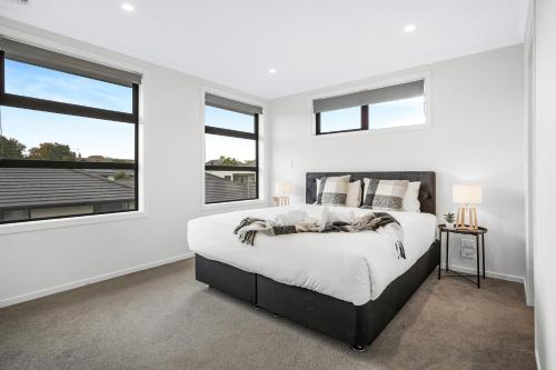 a white bedroom with a large bed and two windows at Spacious Stunner! Central, King Bed -By KOSH BNB in Hamilton