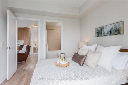 a white bedroom with a large bed with pillows at Belarte Suites - Downtown Toronto - CN Tower & Rogers Centre in Toronto