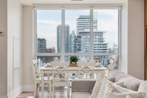 a dining room with a table and a large window at Belarte Suites - Downtown Toronto - CN Tower & Rogers Centre in Toronto