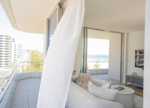 a living room with a white couch and a balcony at Kirra Point Holiday Apartments in Gold Coast