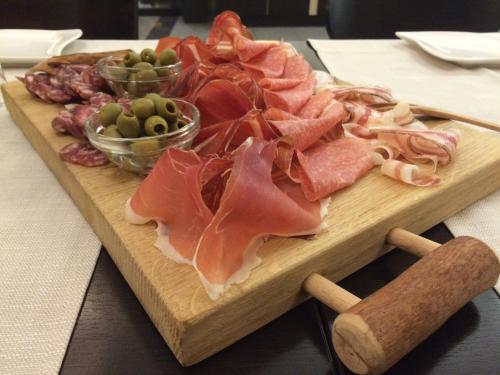 a cutting board with meats and olives on a table at Hotel Kras in Postojna
