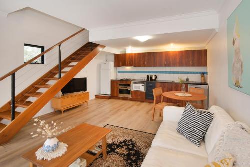 a living room with a white couch and a kitchen at MARGARET FOREST RETREAT Apartment 129 - Located within Margaret Forest, in the heart of the town centre of Margaret River, spa apartment! in Margaret River Town