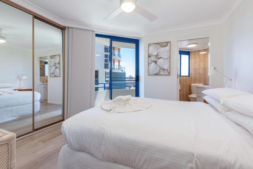 a white bedroom with a large bed and a bathroom at Heritage 301 in Tuncurry