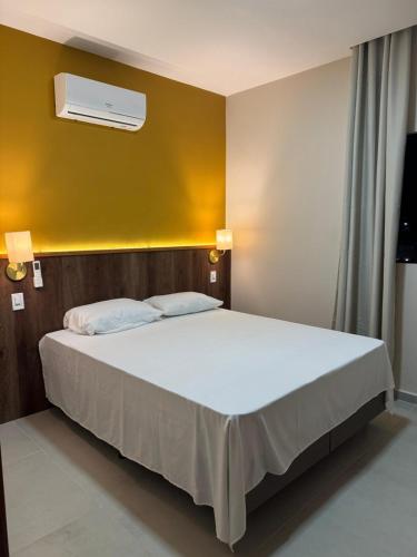 a bedroom with a white bed with a yellow wall at Casa aconchegante com piscina in Marechal Deodoro