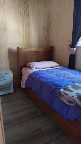una camera da letto con un letto con un piumone blu di Cabañas Kapüra a Hornopiren