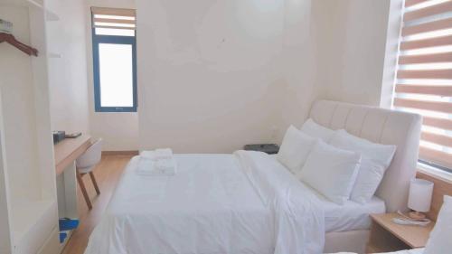 a white bed with white sheets and pillows in a room at At De June Homestay 203 in Cu Lao Thu
