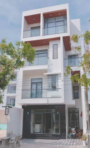 a tall white building with windows and trees at At De June Homestay 203 in Cu Lao Thu