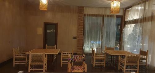a dining room with tables and chairs and a window at Houarra in Aït Ayad