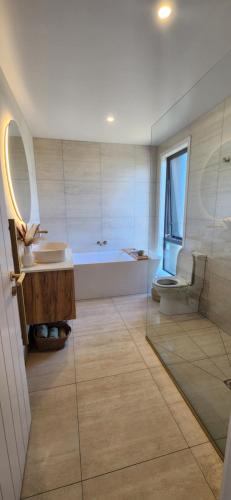 a bathroom with a tub and a sink and a toilet at Coastal Haven, Ahipara Escape in Ahipara
