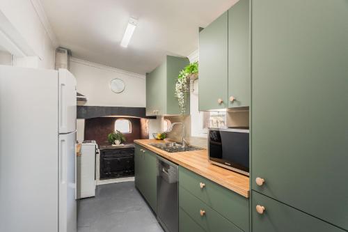 une cuisine avec des armoires vertes et un réfrigérateur blanc dans l'établissement Maranka Homestead, à Waikerie