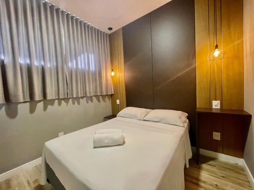 a small room with a bed with white sheets at Eleganz Suítes Exclusive Centro in Gramado