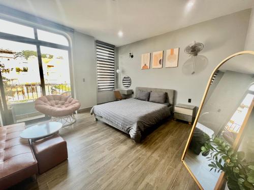 a bedroom with a bed and a chair and a mirror at Green House - Căn hộ có bếp riêng in Da Lat