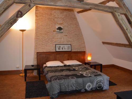 a bedroom with a bed and a brick wall at Moulin atypique du XVème siècle avec jardin clos - FR-1-381-483 in Arpheuilles