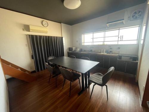 a room with a table and chairs and a kitchen at 徳治郎の宿 in Izumi-Sano