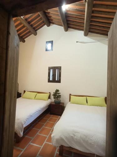 two beds in a room with wooden ceilings at Old Min House Building 3 in Ch'iung-lin