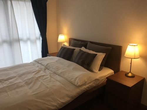 a bed with white sheets and pillows next to a window at Apartment in Narita 225 in Narita