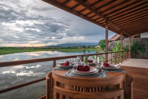 Una mesa en un balcón con vista a un río. en The Manik Kalisada, en Tegallengah