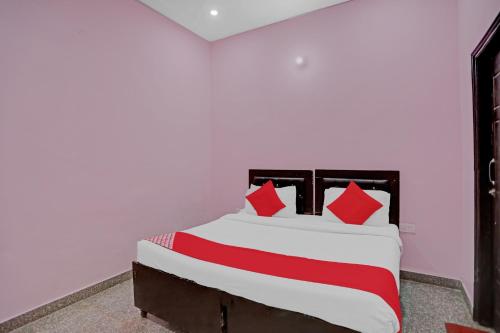 a bedroom with a white bed with red pillows at Hotel O AKKI RESIDENCY in Noida