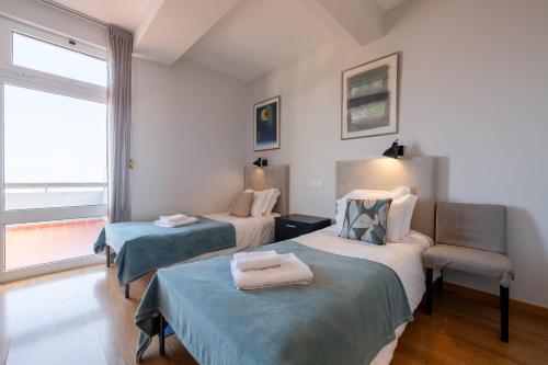 Una habitación con dos camas y una silla y una ventana. en Casa Branca Apartments by TrIp2Portugal, en Funchal