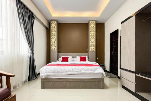 a bedroom with a large bed with red pillows at RedDoorz Syariah at Homestay Haji Soma Makale in Pongtiku Airport