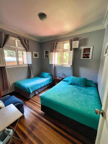 a bedroom with two beds and two windows at Hostal Boonen in Santiago