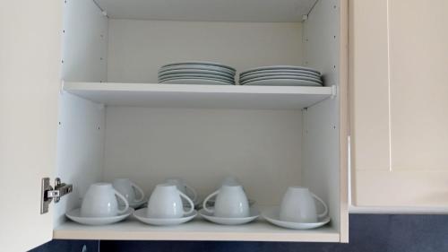 a cupboard filled with white dishes and plates at IaM 3 Zimmer 90 qm Küche Badezimmer kraftraum 44 u in Plettenberg
