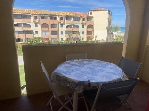 une table et des chaises sur un balcon avec vue sur un immeuble dans l'établissement Studio Cabine avec Terrasse et Parking à 100m de la Plage - FR-1-782-73, au Barcarès