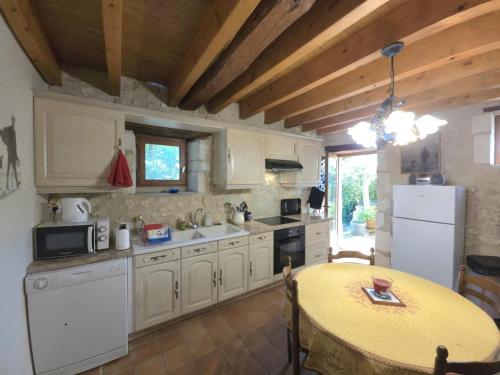 une cuisine avec des armoires blanches et une table à l'intérieur dans l'établissement Maison de charme à Brantôme, animaux admis, parking inclus - FR-1-616-461, à Brantôme