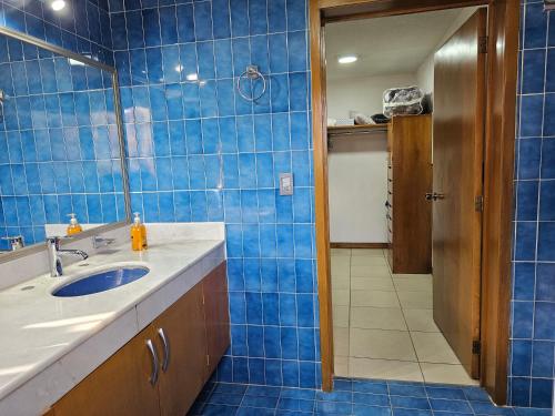 a blue tiled bathroom with a sink and a mirror at Habitación #1 Mascota in Guadalajara