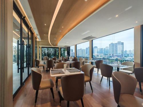 a restaurant with tables and chairs and large windows at Wanda Jin Residences The Ease Sierra Bangkok in Bangkok