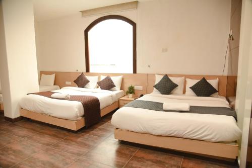 two beds in a room with a window at Hotel The Emporio A Boutique Rooms Near Anand Vihar Vaishali Ghaziabad in Ghaziabad