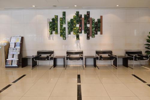 a waiting room with chairs and plants on the wall at Hotel Urbic Kagoshima in Kagoshima