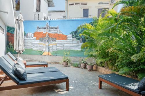 a room with two chairs and a wall with a mural at Mes trois coeurs in Phumĭ Réach Born