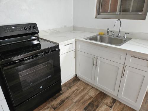 a kitchen with a black stove and a sink at Tulu Famaguon Newly Renovated 2 BR 1BA Entire Apartment Free Wifi, Continental Breakfast, Parking in Tamuning