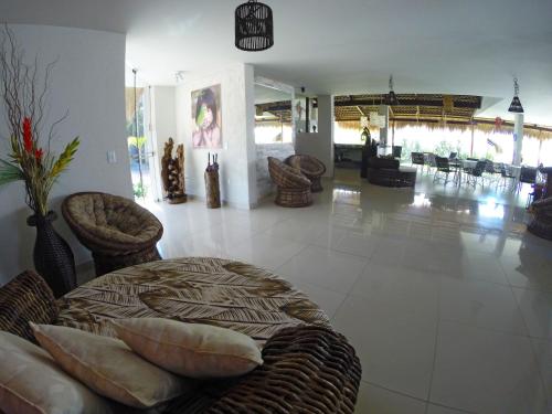 a lobby with a table and chairs in a room at Oasis Tajaja Pousada in Jacumã