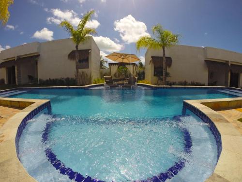 a large swimming pool in front of a building with palm trees at Oasis Tajaja Pousada in Jacumã