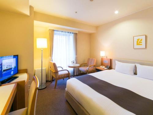 a hotel room with a bed and a television at Rembrandt Hotel Atsugi in Atsugi