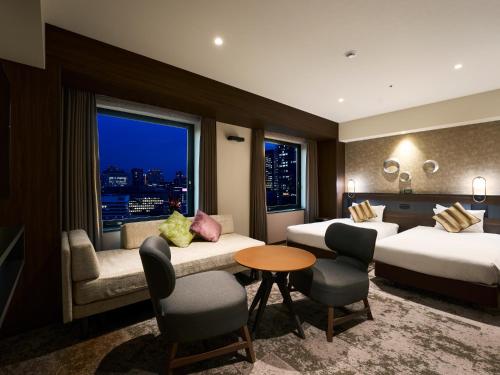 a hotel room with two beds and a window at Hotel Elcient Osaka Umeda in Osaka