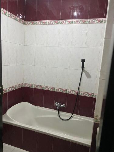 a bath tub with a hose attached to the wall at Moza House Near Alun-Alun Wonosobo in Wonosobo