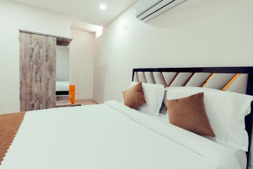a bedroom with a large white bed with pillows at Vaaraahi Hotels in Hyderabad