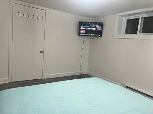 a room with a bed and a tv on the wall at 10 minutes to Montreal entire place 2 bedrooms private entrance in Laprairie