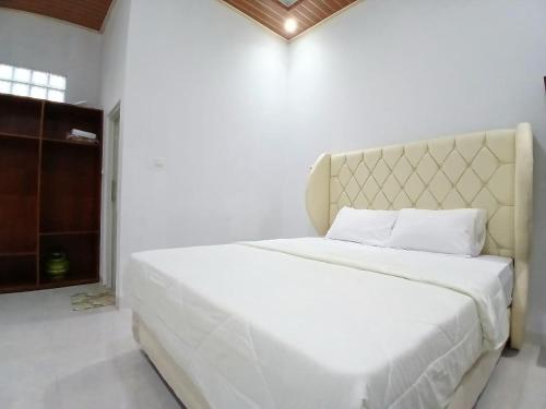a bedroom with a large white bed with a large headboard at D'Bondowoso Homestay Magelang RedPartner in Sumberrejo